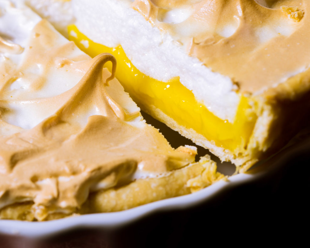 The side of a slice of lemon meringue pie coming out the dish.